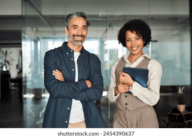 Two diverse business partners, employees or executives standing in office looking at camera. Man and woman sales managers, company workers, consultancy professionals posing for corporate portrait. - Powered by Shutterstock