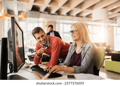 Two diverse colleagues using a computer together in the office - Powered by Shutterstock