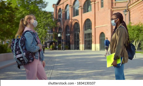 Two Diverse College Friends In Mask Meeting Outdoors University Building 