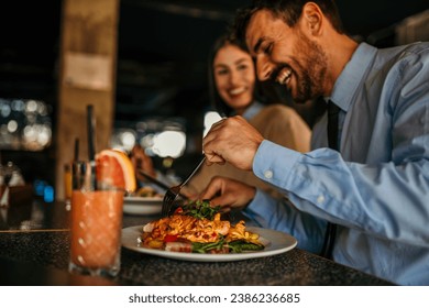 Two diverse companions enjoying a friendly lunch outing at a popular restaurant, basking in the warmth of the atmosphere while sipping on refreshing beverages - Powered by Shutterstock