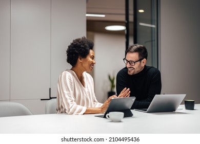 Two diverse coworkers, talking about their day at work. - Shutterstock ID 2104495436