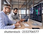 Two diverse crypto traders brokers stock exchange market investors discussing trading charts research reports growth using pc computer looking at screen analyzing invest strategy, financial risks.