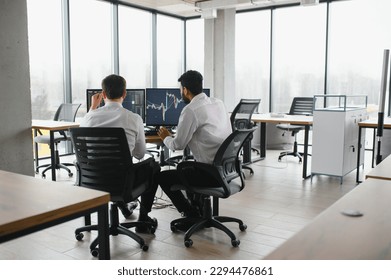 Two diverse crypto traders brokers stock exchange market investors discussing trading charts research reports growth using pc computer looking at screen analyzing invest strategy, financial risks - Shutterstock ID 2294476861