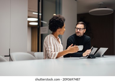Two diverse employees, taking a breather and talking to each other. - Shutterstock ID 2093697487