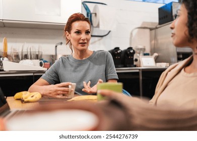 Two diverse female coworkers are enjoying a coffee break in the kitchen of their coworking space, engaging in conversation and fostering a sense of community - Powered by Shutterstock