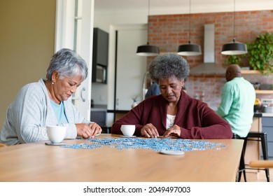 Two diverse female friends sitting in kitchen with coffee and doing puzzles. socialising with friends at home. - Powered by Shutterstock