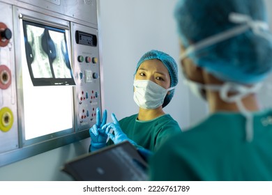 Two diverse female surgeons discussing x-ray on lightbox in operating theatre. Hospital, medical and healthcare services. - Powered by Shutterstock