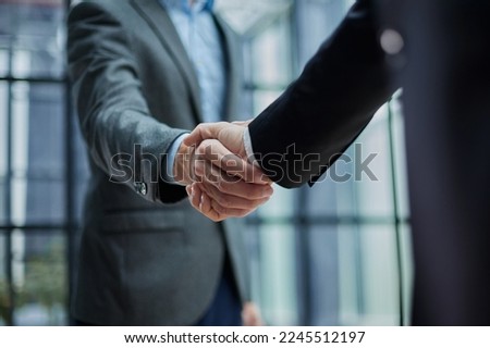 Two diverse professional business men executive leaders shaking hands at office meeting