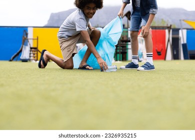 Two diverse schoolboys collecting rubbish for recycling in schoolyard, with copy space. Education, inclusivity, elementary school and learning concept. - Powered by Shutterstock