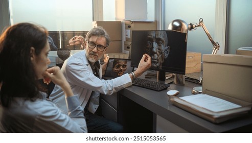 Two diverse scientists discuss 3D model of human head anatomy displayed on PC and tablet computer screens, conduct scientific research. Archaeologists or paleontologists work in archaeological lab. - Powered by Shutterstock