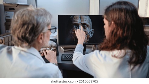 Two diverse scientists discuss 3D model of human head anatomy displayed on PC and tablet computer screens, conduct historical research. Archaeologists or paleontologists work in archaeological lab. - Powered by Shutterstock