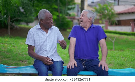 Two diverse senior talking and laughing sitting on park bench in Brazil. Candid authentic people real life laugh and smile in old age retirement golden years - Powered by Shutterstock