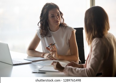 Two diverse serious businesswomen discussing business project working together in office, serious female advisor and client talking at meeting, focused executive colleagues brainstorm sharing ideas