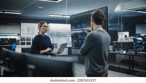 Two Diverse Software Developers Having a Meeting in a Conference Room. Female and Male Tech Industry Engineers Brainstorming Ideas for Their Neural Network Blockchain Startup