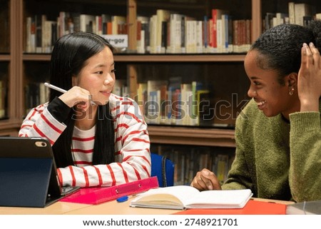 Two diverse students studying and collaborating on a project in a school library