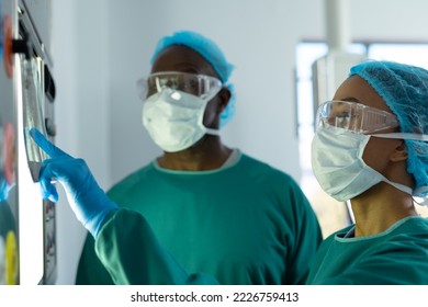 Two diverse surgeons discussing x-ray on lightbox in operating theatre. Hospital, medical and healthcare services. - Powered by Shutterstock