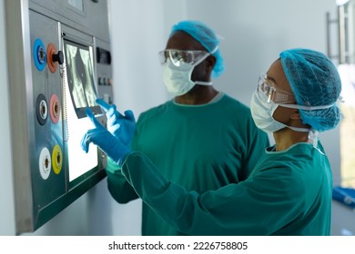 Two diverse surgeons studying x-ray on lightbox in operating theatre. Hospital, medical and healthcare services.