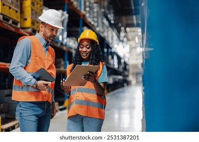 Two diverse warehouse workers are reviewing inventory information, one holding a digital tablet and the other a clipboard, demonstrating efficient stock management - Powered by Shutterstock