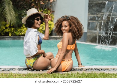 Two diverse women in bikinis relaxing poolside at a tropical resort, enjoying the sun and the refreshing atmosphere - Powered by Shutterstock