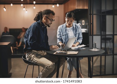 Two Diverse Young Businesspeople Working On A Project Together At A Table In A Modern Office