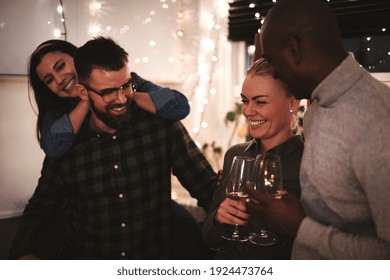 Two diverse young couples laughing and talking over wine while having fun together at an evening party - Shutterstock ID 1924473764
