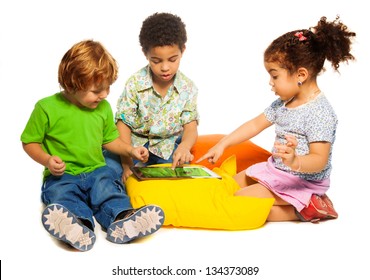 Two diversity looking boys and girl playing with tablet computer sitting on pillows - Powered by Shutterstock