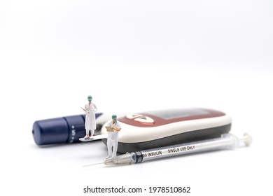 Two Doctor Miniature Figure With Patient File Standing On Glucose Meter With Lancet And Insulin Syringe On White Background. Using As Diabetes, Glycemia, Health Care And People Concept.