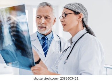 Two doctors examines X-ray scan in clinic. Bones and rib cage, lungs image in hospital. Respiratory diseases, coronavirus treatment. Pneumonia - Powered by Shutterstock