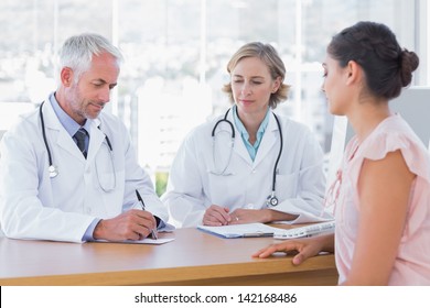 Two Doctors With A Female Patient In A Bright Office