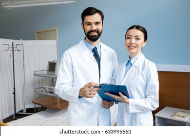 Two Doctors Holding Diagnosis And Posing In Hospital Chamber