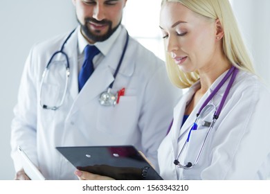 Two doctors holding a folder and talking about patient
