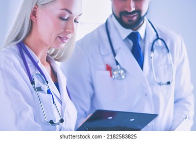 Two doctors holding a folder and talking about patient