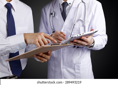 Two doctors holding and talking about patient on black