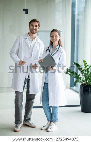 Two doctors talking in the clinics corridor and looking contended