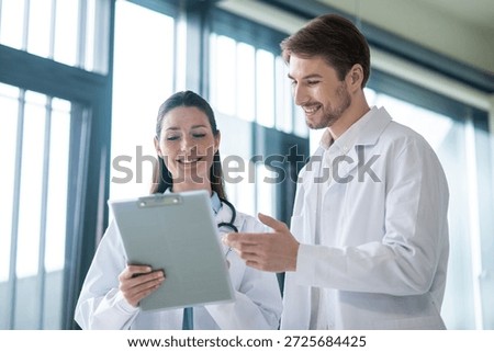 Two doctors talking in the clinics corridor and looking contended