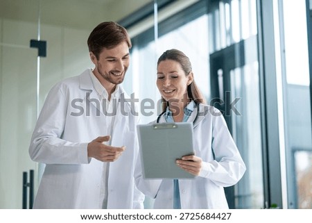 Two doctors talking in the clinics corridor and looking contended