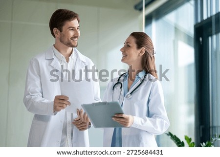 Two doctors talking in the clinics corridor and looking contended
