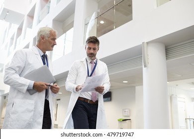 Two Doctors Talking As They Walk Through Modern Hospital