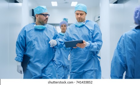 Two Doctors Walking Through Hospital and Discussing Comeing Operation.One Use Tablet in Hands. - Powered by Shutterstock