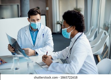 Two doctors wearing protective face masks and cooperating while analyzing medical scan on a meeting at the clinic. - Powered by Shutterstock