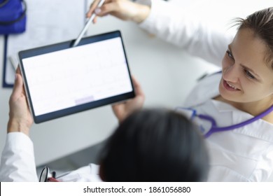 Two Doctors At The Workplace Are Looking At Tablet. Modern Medical Technology Concept