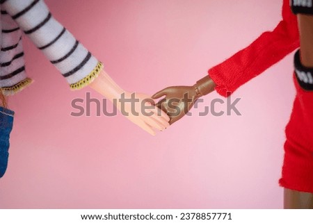 two dolls white and black shake hands with each other