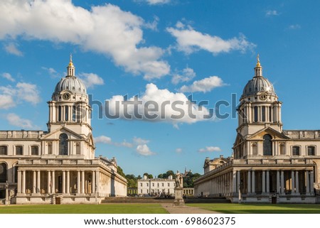 The two domed towers of the Old Royal Naval College, Greenwich, London, England frame a cloud on a summer day