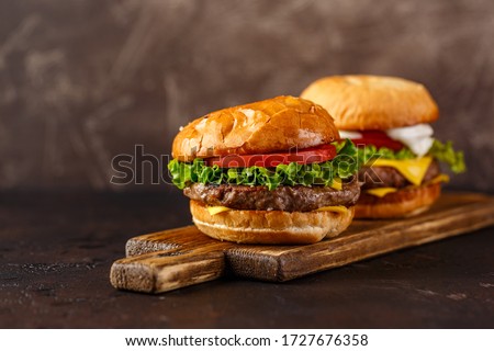 Two double cheeseburger with lettuce, tomato and melted cheese on wooden board