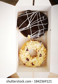 Two doughnuts inside the box. Chocolate and milk. 