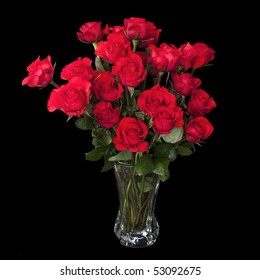 Two Dozen Red Roses Isolated On Black Background With The Green Stems In A Large Glass Vase With Water. Copyspace On All Four Sides.