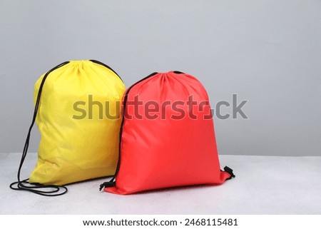 Two drawstring bags on light textured table. Space for text