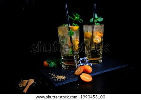 two drinks with mint and kumquat on a black background