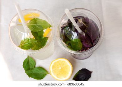 Two drinks: water with lemon and basil leaves