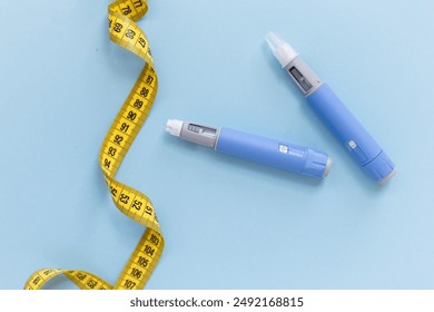 Two drugs injection ozempic for weight loss with a measuring yellow tape on a blue background. Drug pen for diabetics and weight loss, top view. antidiabetic medication or anti-obesity medication - Powered by Shutterstock